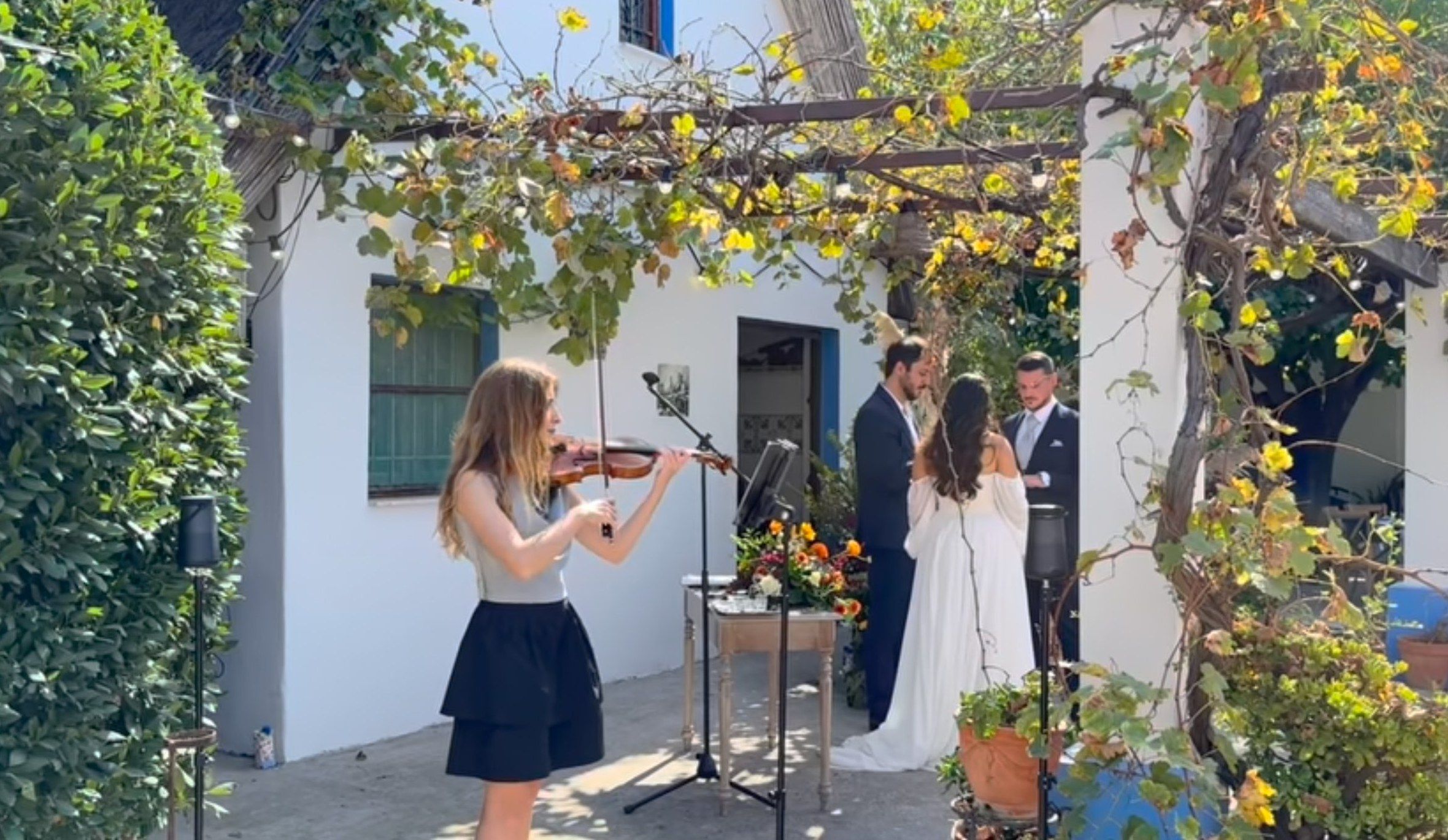 Laura Gallego tocando el violín en directo durante una ceremonia de boda real en un patio